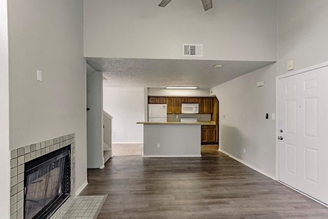 unfurnished living room featuring ceiling fan, a textured ceiling, a fireplace, and dark hardwood / wood-style flooring