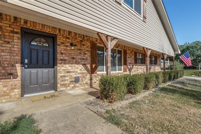 entrance to property with a lawn and covered porch