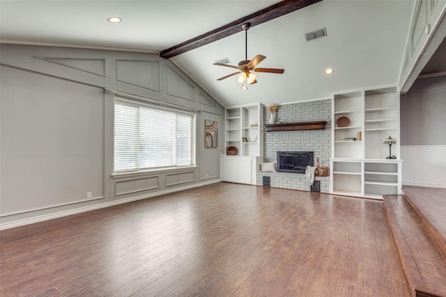 unfurnished living room with built in shelves, lofted ceiling with beams, a brick fireplace, and hardwood / wood-style flooring