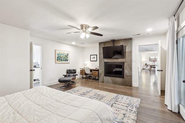 bedroom with wood-type flooring, ceiling fan, and a fireplace