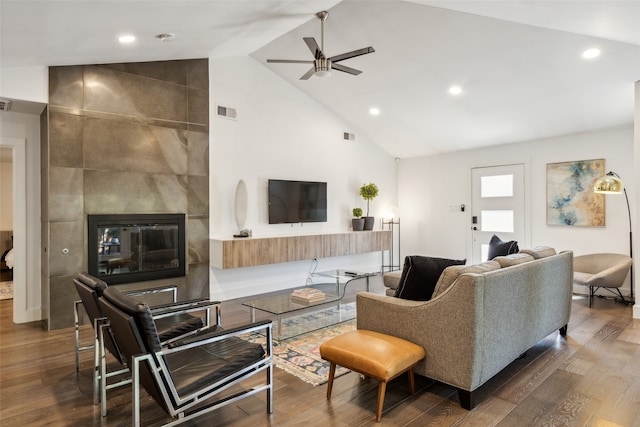 living room featuring a tile fireplace, dark hardwood / wood-style flooring, ceiling fan, and high vaulted ceiling