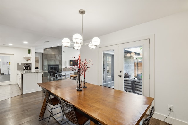 dining space with french doors, dark wood-type flooring, and a tile fireplace