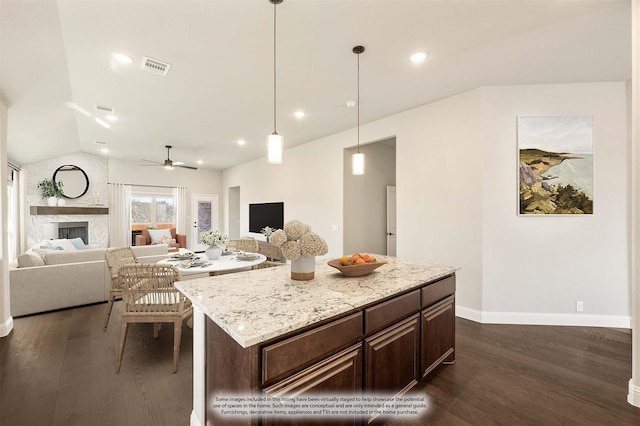 kitchen featuring pendant lighting, a stone fireplace, dark hardwood / wood-style floors, and a kitchen island