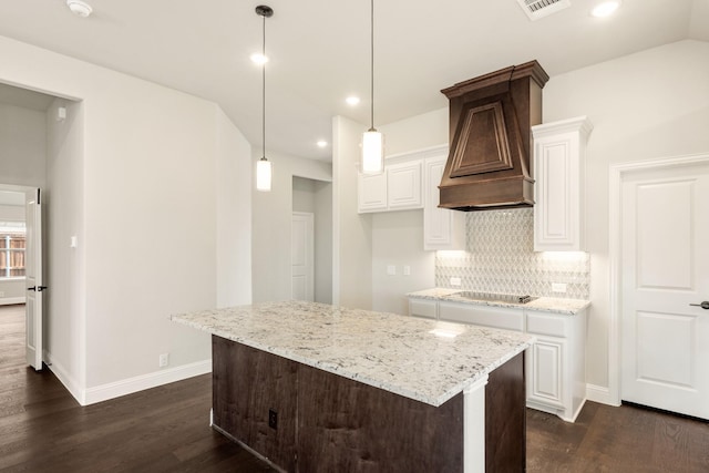 kitchen featuring light stone counters, decorative light fixtures, custom range hood, black electric stovetop, and white cabinets