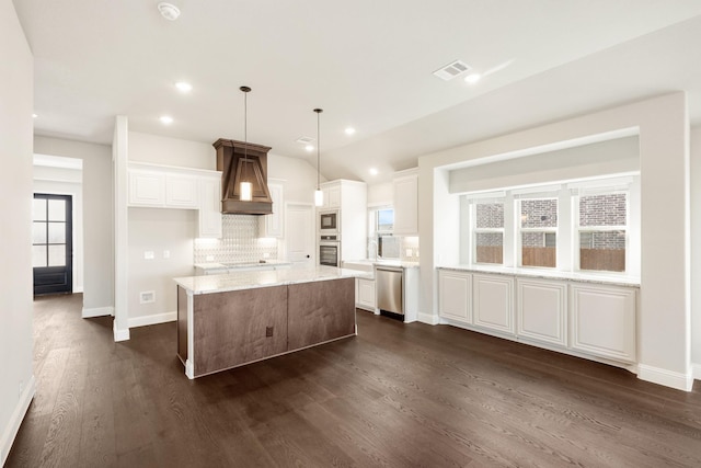 kitchen featuring hanging light fixtures, stainless steel appliances, custom range hood, and white cabinets