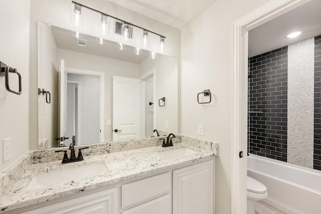 full bathroom featuring tiled shower / bath, vanity, and toilet