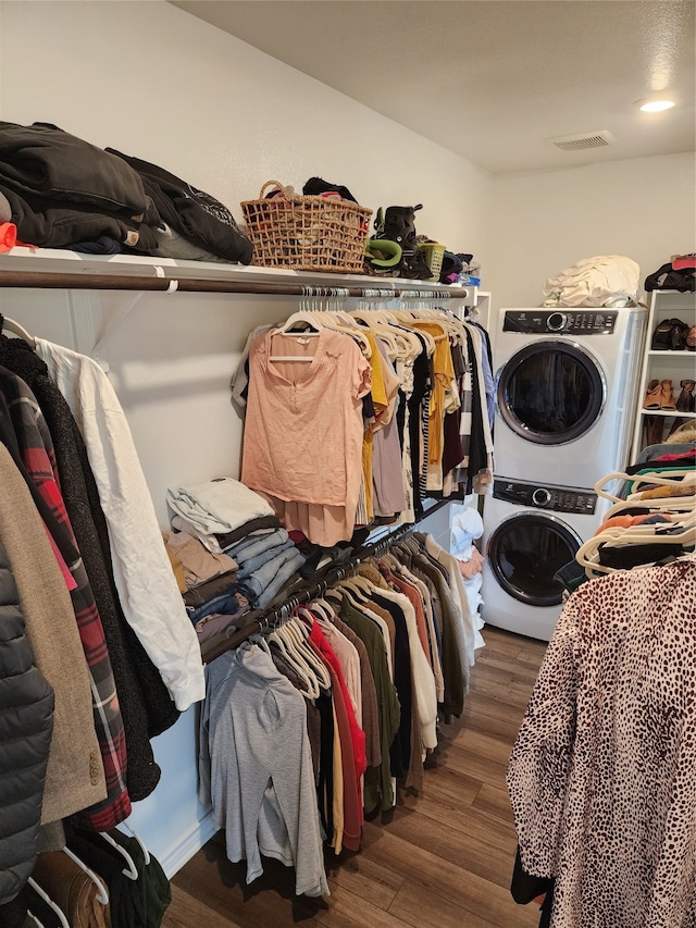 spacious closet with stacked washer and dryer and dark hardwood / wood-style floors