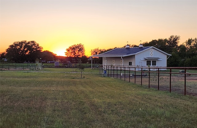 yard at dusk featuring a rural view