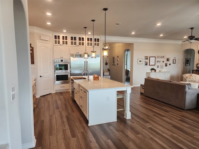 kitchen featuring pendant lighting, a center island with sink, appliances with stainless steel finishes, a kitchen bar, and dark hardwood / wood-style flooring