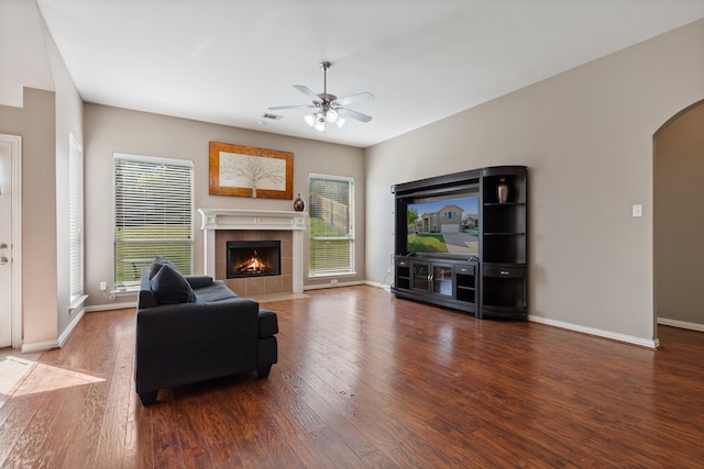 living room with ceiling fan, a tile fireplace, and hardwood / wood-style floors