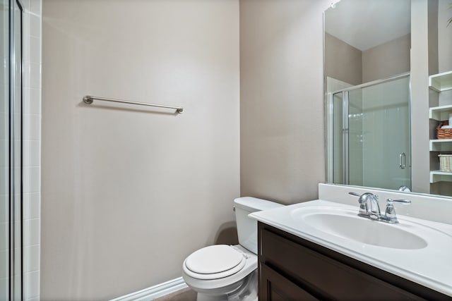 bathroom with a shower with door, vanity, and toilet