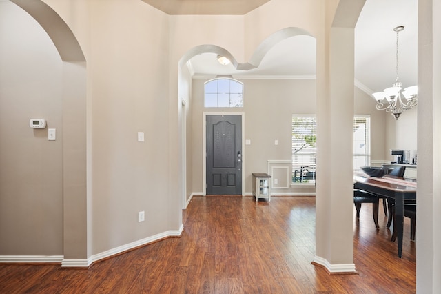 foyer entrance with a notable chandelier, crown molding, dark wood-type flooring, and a wealth of natural light