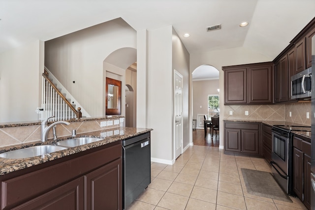 kitchen with light tile patterned flooring, black appliances, dark brown cabinetry, dark stone counters, and sink