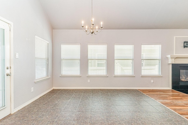 unfurnished dining area featuring a tiled fireplace, hardwood / wood-style floors, and a chandelier