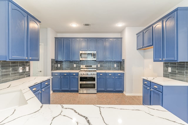 kitchen featuring light stone countertops, appliances with stainless steel finishes, tasteful backsplash, and blue cabinets