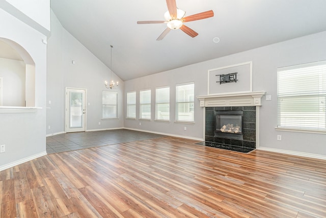 unfurnished living room featuring hardwood / wood-style flooring, plenty of natural light, a fireplace, and ceiling fan with notable chandelier