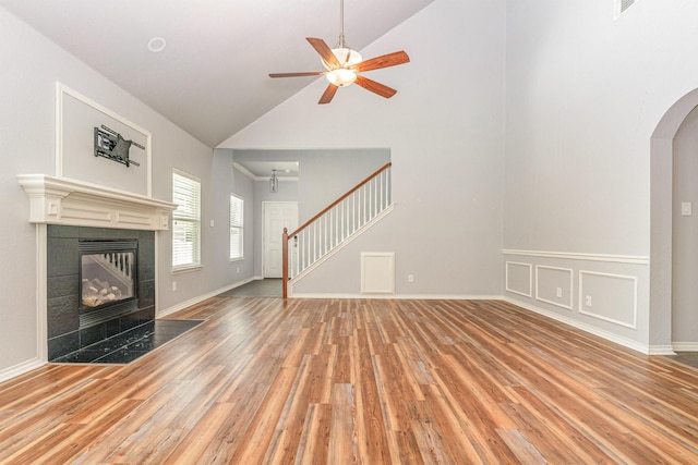 unfurnished living room with a tile fireplace, ceiling fan, high vaulted ceiling, and hardwood / wood-style flooring