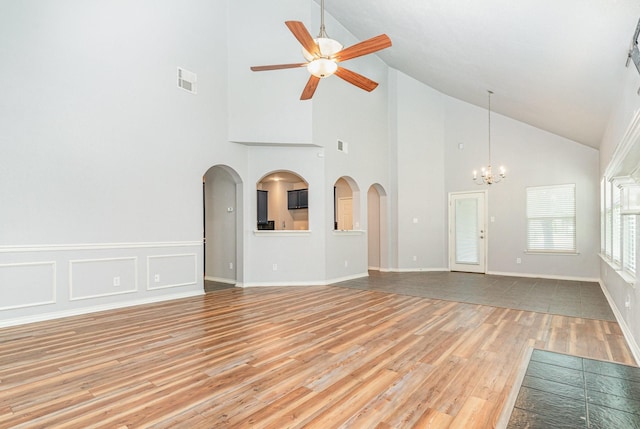 unfurnished living room featuring ceiling fan with notable chandelier, light hardwood / wood-style flooring, and high vaulted ceiling