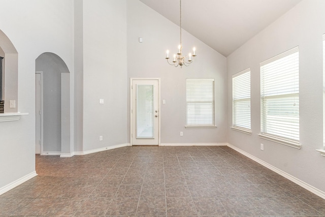 tiled empty room featuring a notable chandelier and high vaulted ceiling