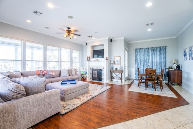 living room featuring ornamental molding, light wood-type flooring, and ceiling fan