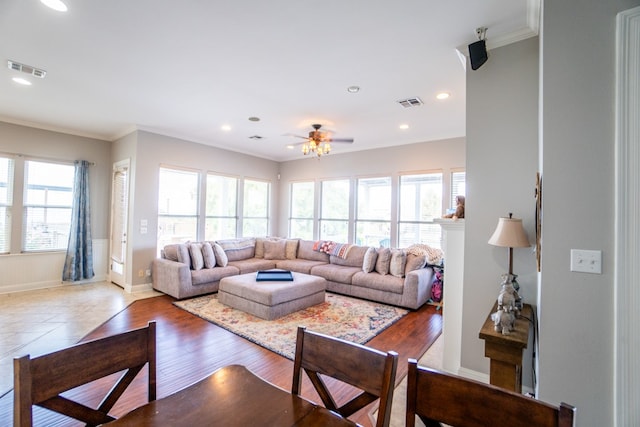 living room featuring ceiling fan, crown molding, light hardwood / wood-style floors, and a healthy amount of sunlight