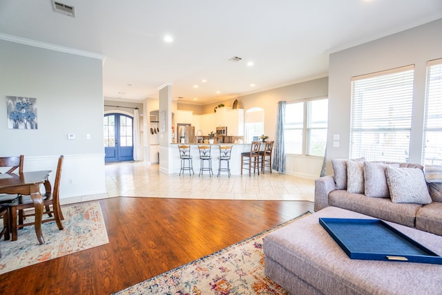 living room featuring light hardwood / wood-style flooring, plenty of natural light, and crown molding