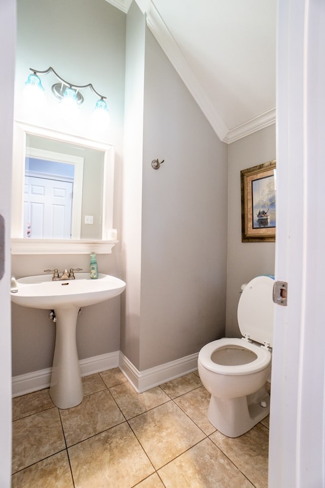 bathroom with crown molding, lofted ceiling, toilet, and tile patterned floors