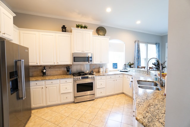 kitchen with appliances with stainless steel finishes, ornamental molding, white cabinetry, and sink