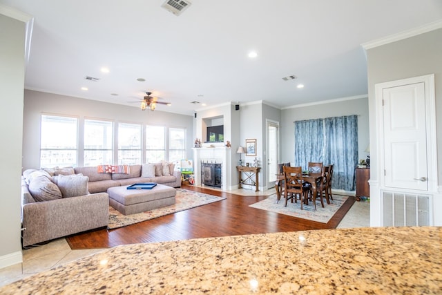 living room with light wood-type flooring, crown molding, and ceiling fan