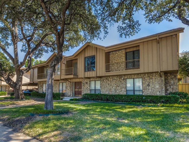 view of property featuring a balcony and a front lawn