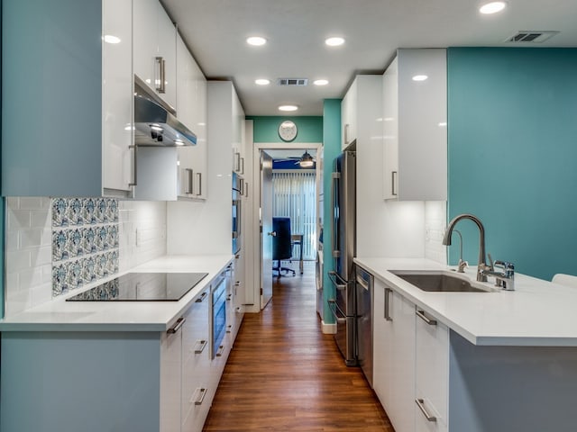 kitchen with appliances with stainless steel finishes, tasteful backsplash, white cabinets, dark hardwood / wood-style floors, and sink