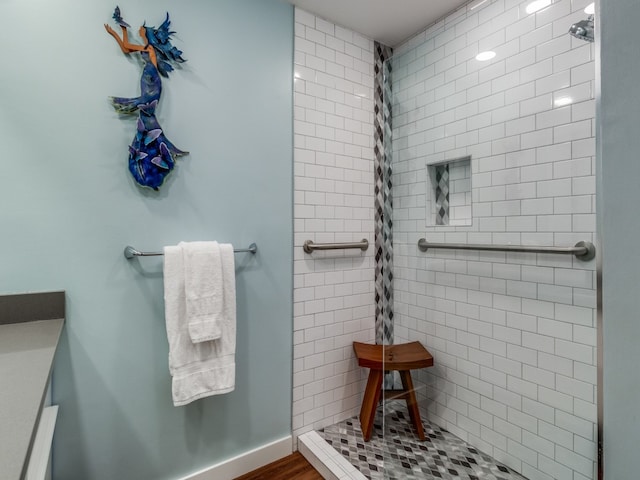 bathroom featuring a tile shower and wood-type flooring