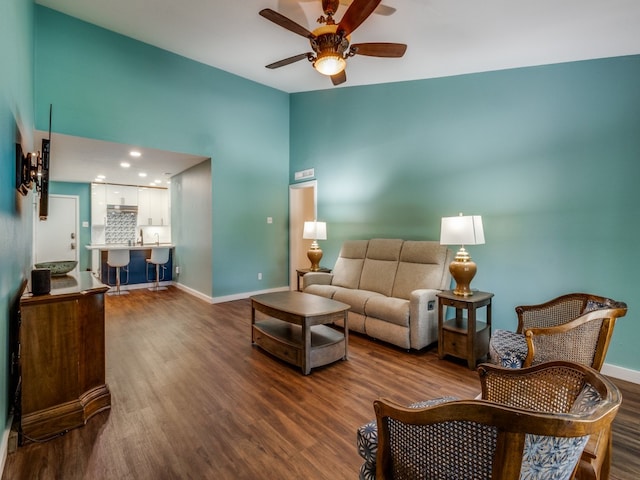 living room with ceiling fan, hardwood / wood-style flooring, and a high ceiling