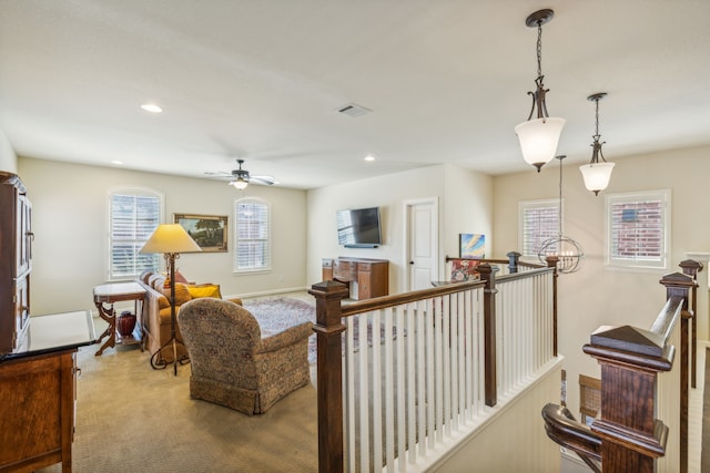 carpeted living room featuring ceiling fan with notable chandelier