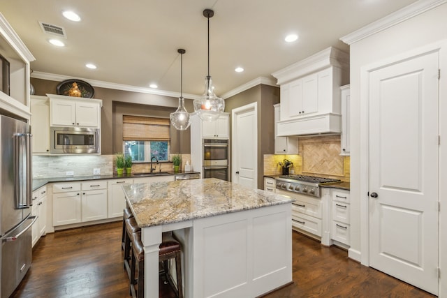 kitchen featuring appliances with stainless steel finishes, white cabinetry, a center island, dark stone counters, and dark hardwood / wood-style floors