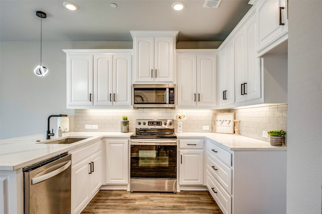 kitchen featuring decorative light fixtures, sink, stainless steel appliances, and white cabinetry