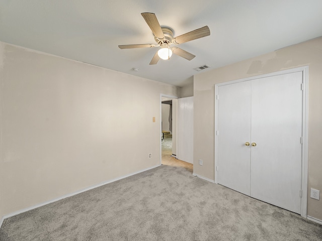 unfurnished bedroom featuring ceiling fan, a closet, and light carpet