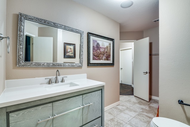 bathroom featuring tile patterned floors, a textured ceiling, vanity, and toilet