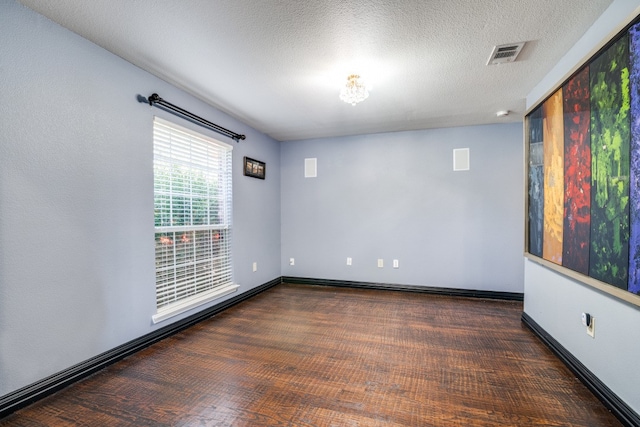 spare room featuring a textured ceiling and dark hardwood / wood-style floors