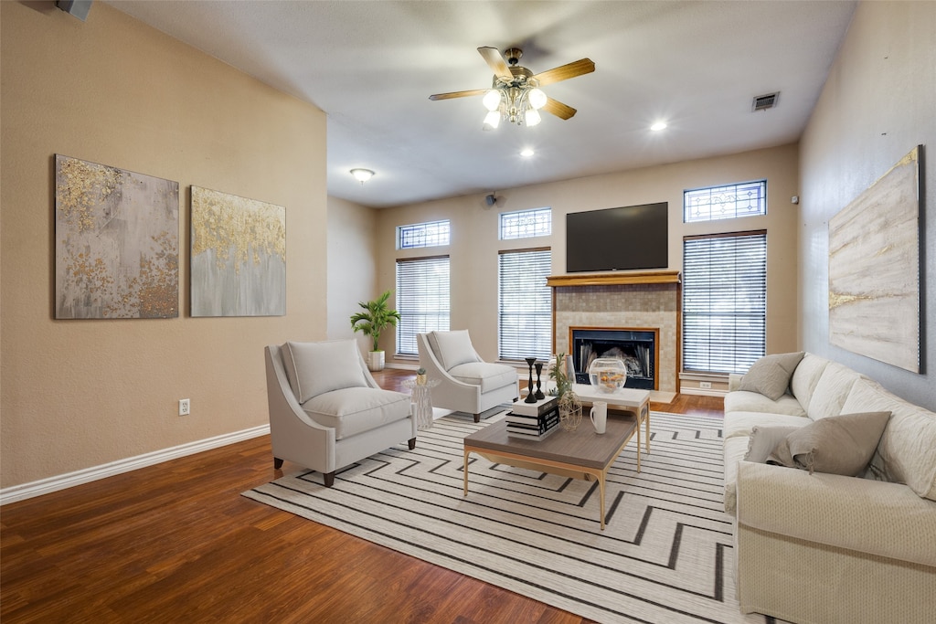 living room with a wealth of natural light, a tiled fireplace, hardwood / wood-style flooring, and ceiling fan