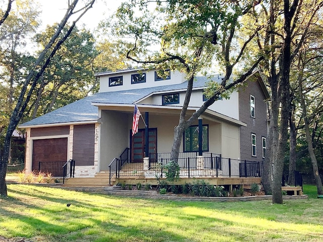 view of front of house featuring stucco siding, a front lawn, a porch, and an attached garage