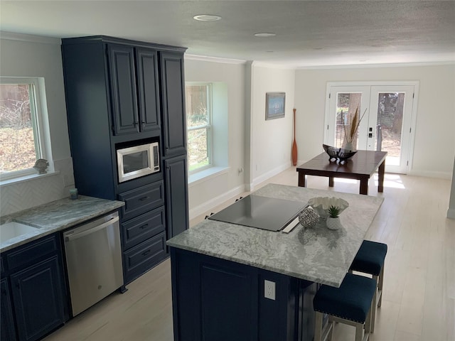 kitchen with a breakfast bar, plenty of natural light, light wood-style flooring, and stainless steel appliances