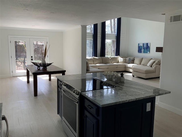 kitchen with light wood-style floors, stainless steel electric range, dark cabinets, and visible vents