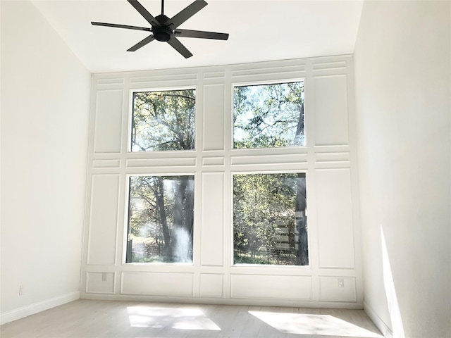 spare room with a decorative wall, baseboards, and a ceiling fan