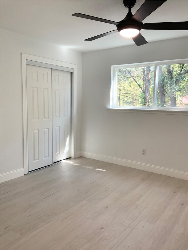 unfurnished bedroom with a closet, a ceiling fan, light wood-type flooring, and baseboards