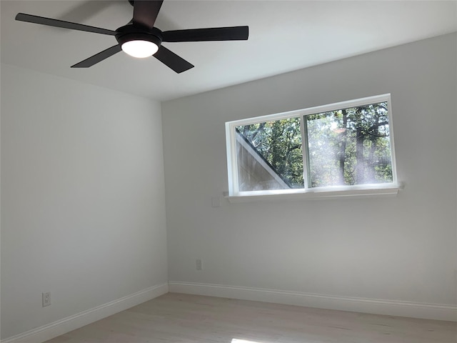 spare room with baseboards, light wood-style flooring, and a ceiling fan