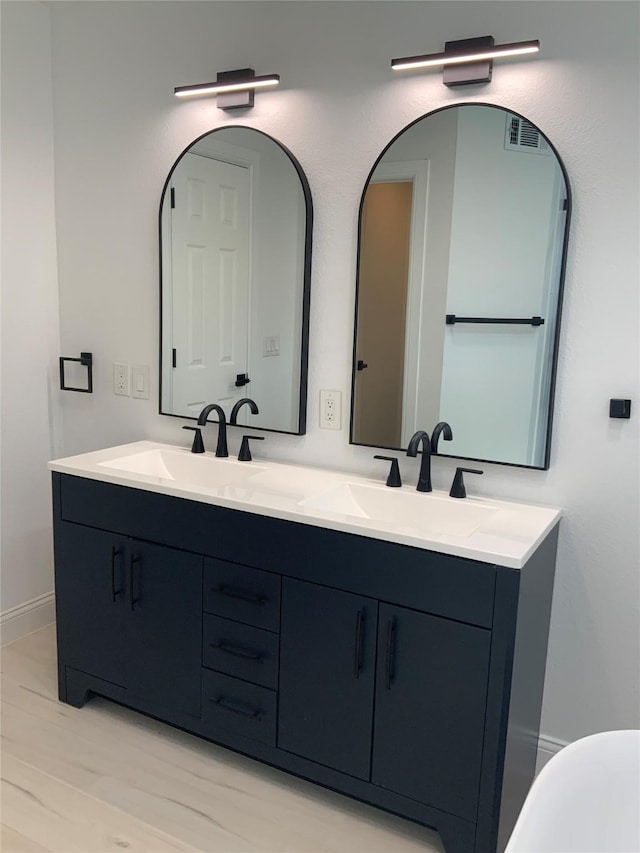 bathroom featuring a sink, visible vents, baseboards, and double vanity