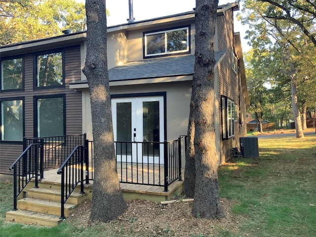 view of front facade with a front yard, central air condition unit, and a shingled roof