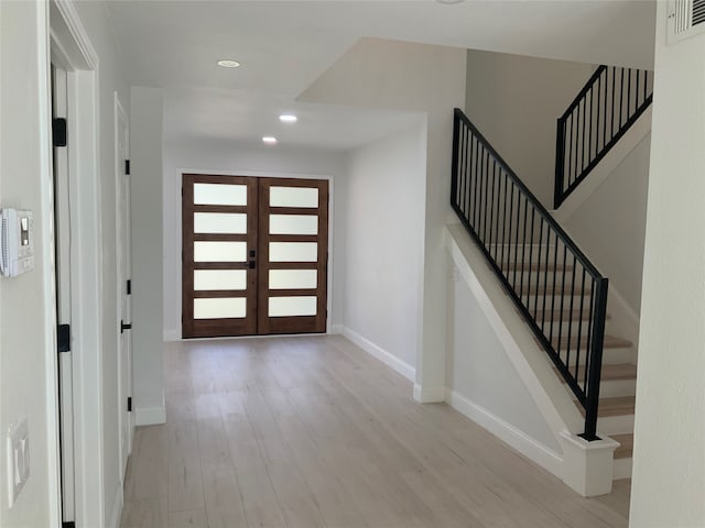 entryway with visible vents, recessed lighting, light wood finished floors, baseboards, and stairs