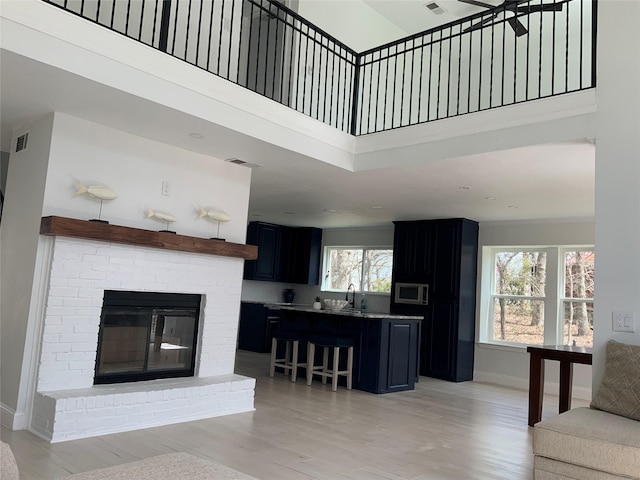 living area featuring a towering ceiling, baseboards, visible vents, and light wood finished floors